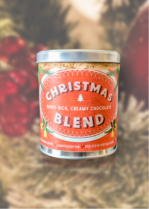 Canister of 'Christmas Blend' coffee against a festive background with ornaments.